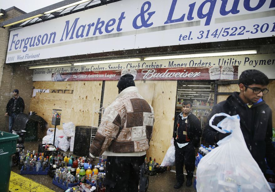 In this Wednesday, Nov. 26, 2014, file photo, Kush Patel, right, carries out bags of merchandise while helping his uncle Andy Patel, rear, clean up the looting damage from Monday&#39;s riots at his store, Ferguson Market and Liquor, in Ferguson, Mo. The store is disputing a new documentary’s claims that surveillance video suggests Michael Brown didn’t rob the store before he was fatally shot by police in Ferguson. One of the filmmakers said he believes the footage shows Brown trading marijuana for a bag of cigarillos early on Aug. 9, 2014, and that Brown intended to come back later for the cigarillos. Store officials said no drug transaction took place and Brown stole the cigarillos while at the store later that day. (AP Photo/David Goldman, File)