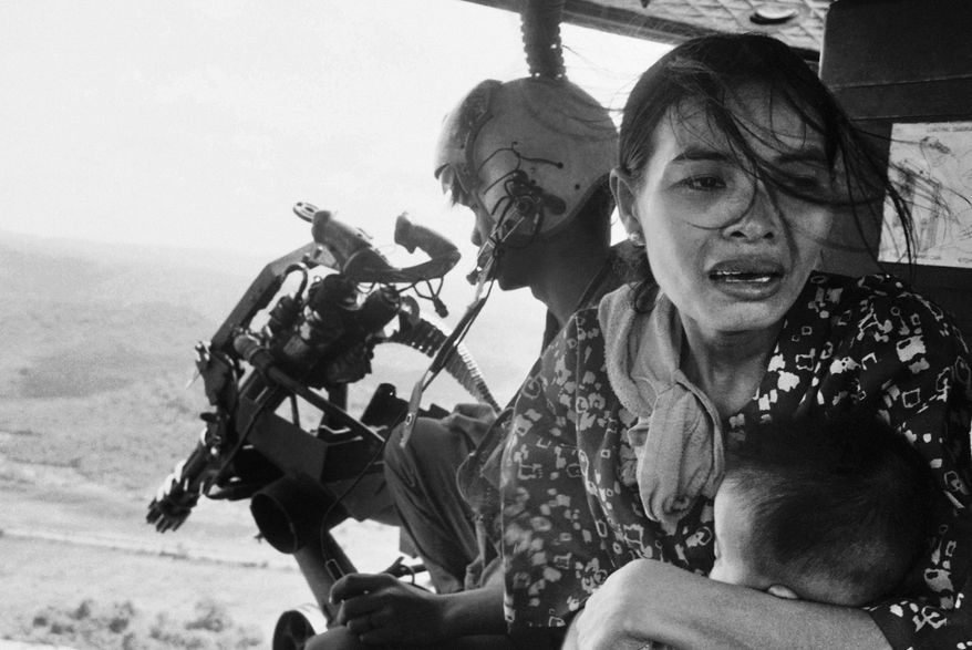 FILE - In this March 22, 1975 file photo, a refugee clutches a baby as a government helicopter gunship carries them away near Tuy Hoa, Vietnam, 235 miles northeast of Saigon. They were among thousands fleeing from Communist advances. (AP Photo/Nick Ut)