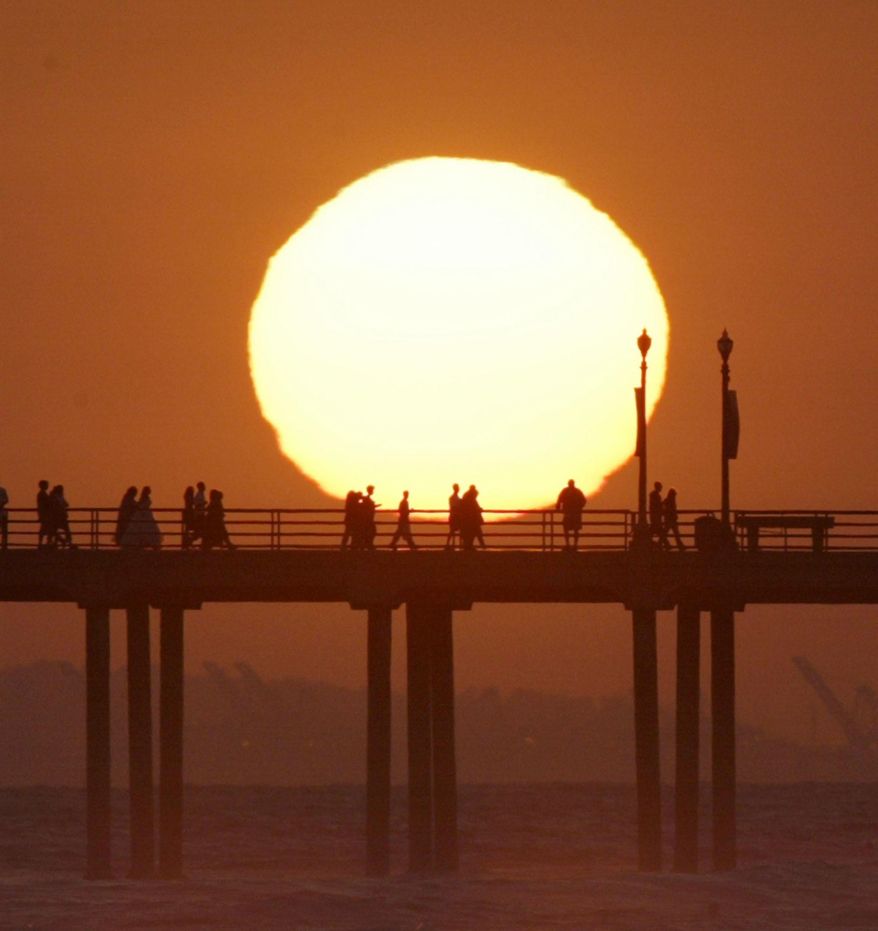 FILE - In this Saturday, May 29, 2004 file photo, people gather on a pier in Huntington Beach, Calif., as the sun sets. AP Photographer Nick Ut will be retiring from the AP in March 2017 after 51 years of taking photographs from the front lines of the Vietnam War to the red carpets of Hollywood. (AP Photo/Nick Ut)