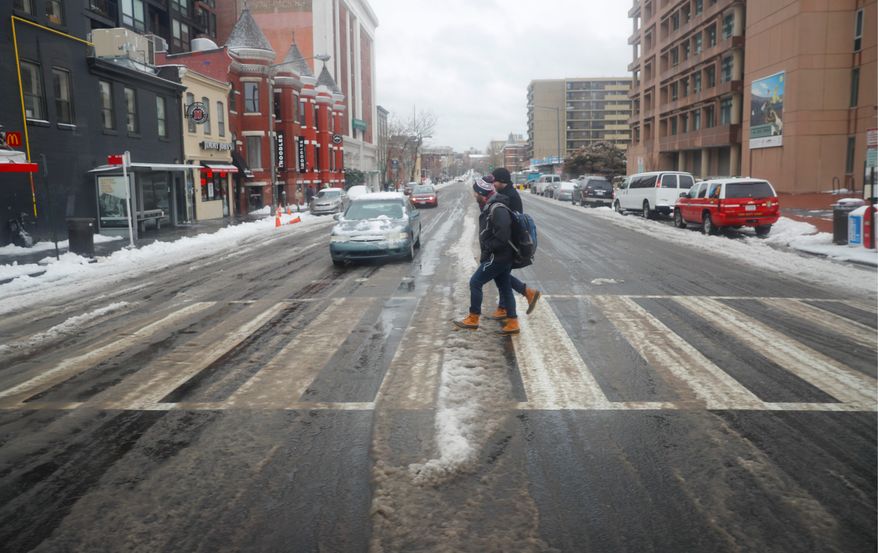Pedestrians use the crosswalk at U Street in lighter than normal traffic in the District on Tuesday. A storm of snow and freezing rain covered most of the region. (Associated Press)