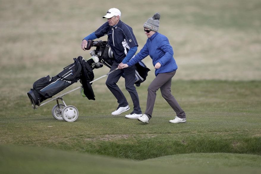 Woman golfer Jeanette Siehenthiler and her caddie walk to a green during a round of golf after it was announced that women will be admitted as members of Muirfield Golf Club after a membership ballot was held by The Honourable Company of Edinburgh Golfers, in Gullane, Scotland Tuesday, March 14, 2017. Muirfield Golf Club voted Tuesday to admit female members for the first time in its 273-year history, paving the way for the Scottish golf club to again host the British Open. ( Jane Barlow/PA via AP)