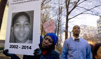 FILE - In this Dec. 1, 2014 file photo, Tomiko Shine holds up a picture of Tamir Rice during a protest in Washington. A 911 dispatcher who took a call that led to a white police officer&#39;s fatal shooting of Rice, a 12-year-old black boy who&#39;d been playing with a pellet gun outside a Cleveland recreation center, has been suspended for eight days. Police Chief Calvin Williams stated in a disciplinary letter Constance Hollinger violated protocol. (AP Photo/Jose Luis Magana, File)