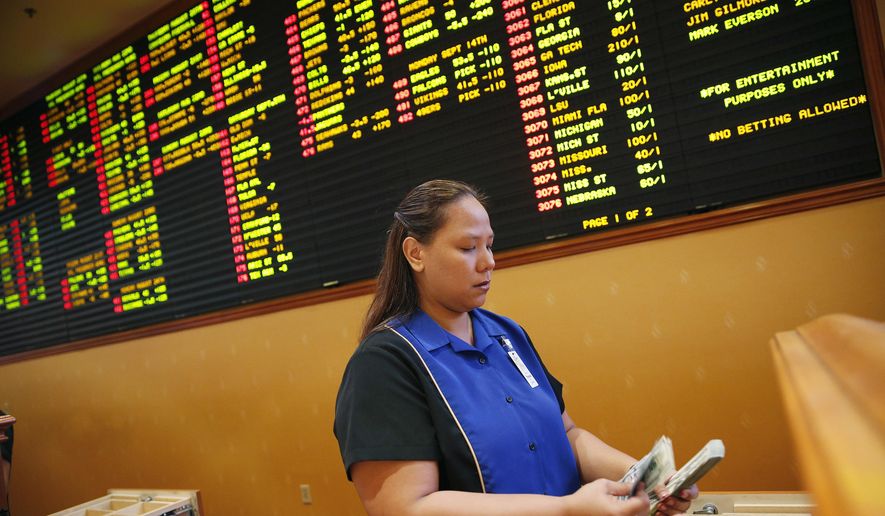 FILE - In this Aug. 20, 2015, file photo, Therese Duenas counts money as she takes bets in the sports book at the South Point hotel and casino in Las Vegas. Las Vegas casinos can&#x27;t agree on an NCAA tournament favorite, with favorites changing within hours. (AP Photo/John Locher, File) **FILE**