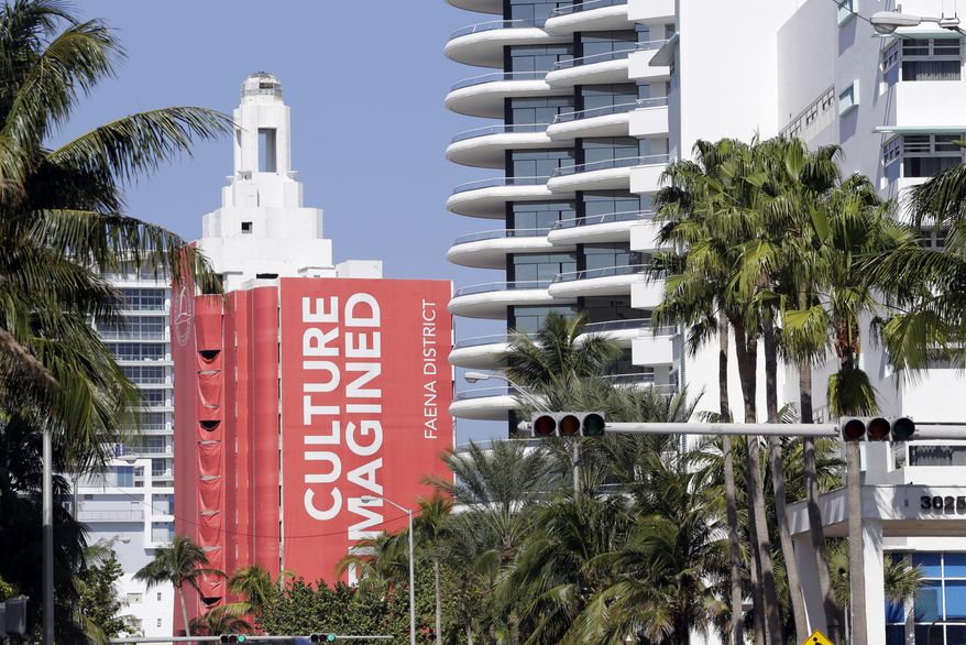 In this Tuesday, Feb. 14, 2017 photo, a mural identifies buildings in the Faena District on Collins Ave. in the Mid-Beach neighborhood of Miami Beach, Fla. Faena House, center, and the Faena Hotel, right, are part of a cluster of buildings developed by Argentine hotel magnate Alan Faena, where decaying structures and empty parking lots are giving way to opulent hotels, condos, and a performing arts center. (AP Photo/Lynne Sladky)