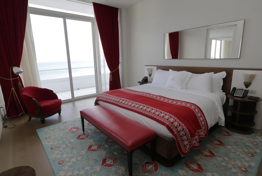 In this Monday, Feb. 27, 2017 photo, an oceanfront room in a two-bedroom suite with the signature red and teal blue color scheme is shown in the Faena Hotel in Miami Beach, Fla. The beachfront hotel is the flagship of Faena District, a cluster of buildings developed by Argentine hotel magnate Alan Faena where decaying structures and empty parking lots are giving way to opulent hotels, condos, and a performing arts center. (AP Photo/Lynne Sladky)