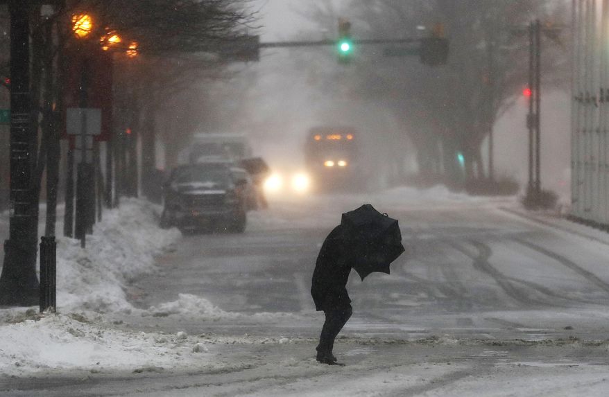 A person hunches while walking against strong winds in Jersey City, N.J., during a snowstorm, Tuesday, March 14, 2017. (AP Photo/Julio Cortez)