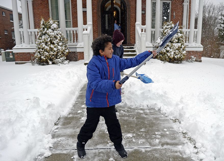 Jayce Petrucci, 10, gives his shovelful of snow a heave as he and Linda Dick clear the walk to their apartment building on Broadway in Norwich, Conn., as a winter storm blankets the region in snow Tuesday, March 14, 2017. (Sean D. Elliot/The Day via AP)