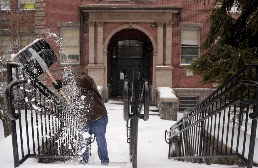 Charles Reese, head custodian at Yonkers Public School 17, clears snow from a set of stairs in front of the school during a snow storm, Tuesday, March 14, 2017, in Yonkers, N.Y. New York Gov. Andrew Cuomo has declared a state of emergency Tuesday for all of New York's 62 counties, including New York City's five boroughs. (AP Photo/Julie Jacobson)