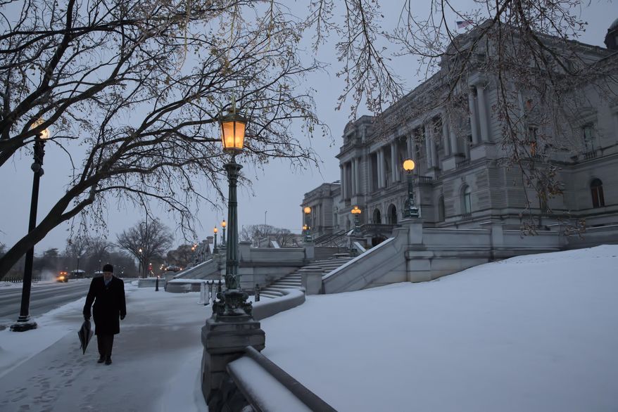 A man walks past the Library of Congress in the snow, on Capitol Hill in Washington, early Tuesday, March, 14, 2017. A late-season storm is dumping a messy mix of snow, sleet and rain on the mid-Atlantic, complicating travel, knocking out power and closing schools and government offices around the region. (AP Photo/J. Scott Applewhite)