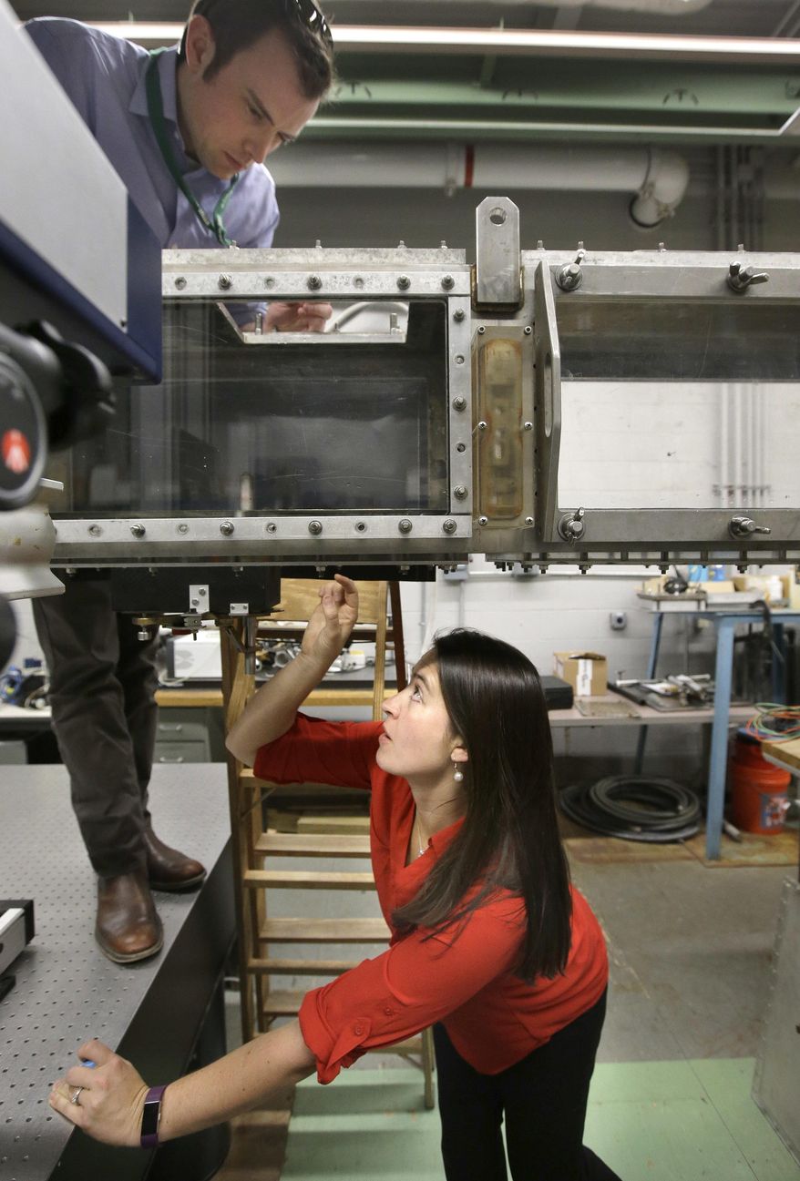 In this Thursday, March 2, 2017 photo, engineer David Wade, top, and marine mammal biologist Christin Murphy, bottom, position a seal whisker inside a water tunnel in a laboratory at the Naval Undersea Warfare Center, in Newport, R.I. Scientists think real seals, specifically their whiskers, may be the key to a new way for ships and underwater vehicles to sense their environment. (AP Photo/Steven Senne)