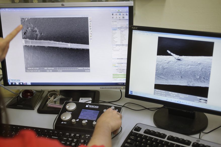 In this Thursday, March 2, 2017, photo, marine mammal biologist Christin Murphy, hands only, displays close-up images of seal whiskers generated by an electron microscope in a laboratory at the Naval Undersea Warfare Center, in Newport, R.I. Scientists think real seals, specifically their whiskers, may be the key to a new way for ships and underwater vehicles to sense their environment. (AP Photo/Steven Senne)