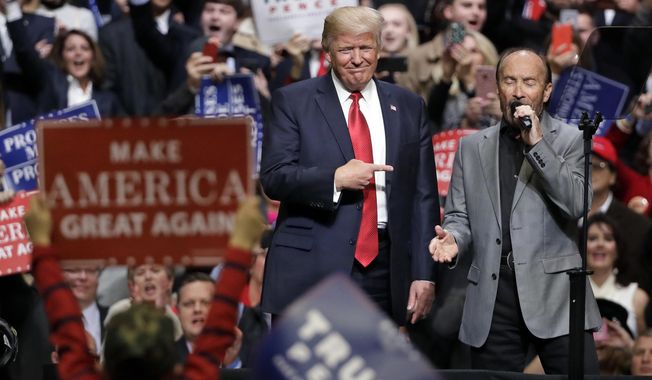 Then-President Donald Trump stands on stage with singer Lee Greenwood as Greenwood sings &quot;God Bless the USA&quot; at a rally in Nashville, Tenn., on Wednesday, March 15, 2017. (AP Photo/Mark Humphrey) **FILE**
