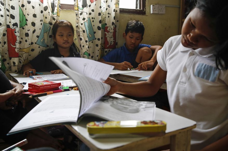 In this March 11, 2017, photo, Christian Burmese refugees study during an English lesson in Kuala Lumpur, Malaysia. An Associated Press analysis suggests that the people hurt most by President Donald Trump's planned deep cuts in refugee visas are from not any of the six Muslim countries listed in his travel ban, but Myanmar. (AP Photo/Joshua Paul)