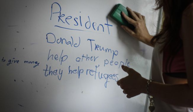 In this March 11, 2017, photo, a volunteer teacher erases the board after her English lesson after teaching Christian Burmese refugees in Kuala Lumpur, Malaysia. An Associated Press analysis suggests that the people hurt most by President Donald Trump&#x27;s planned deep cuts in refugee visas are from not any of the six Muslim countries listed in his travel ban, but Myanmar. (AP Photo/Joshua Paul)