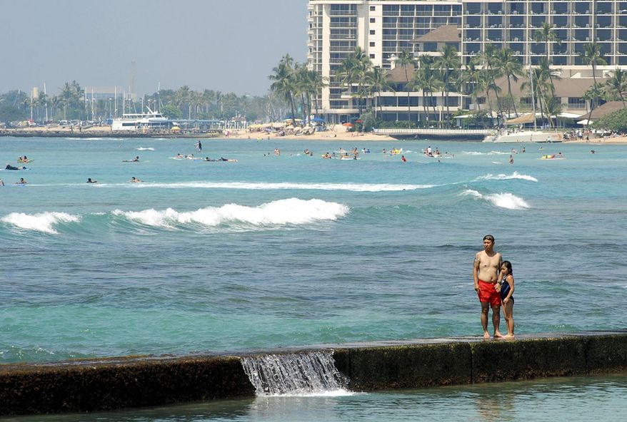 In this Monday, March 13, 2017 photo, people swim off the shore of Waikiki in Honolulu. Hawaii has filed a lawsuit challenging President Donald Trump's revised travel ban, saying the executive order could harm the state's strong tourist economy. (AP Photo/Caleb Jones)