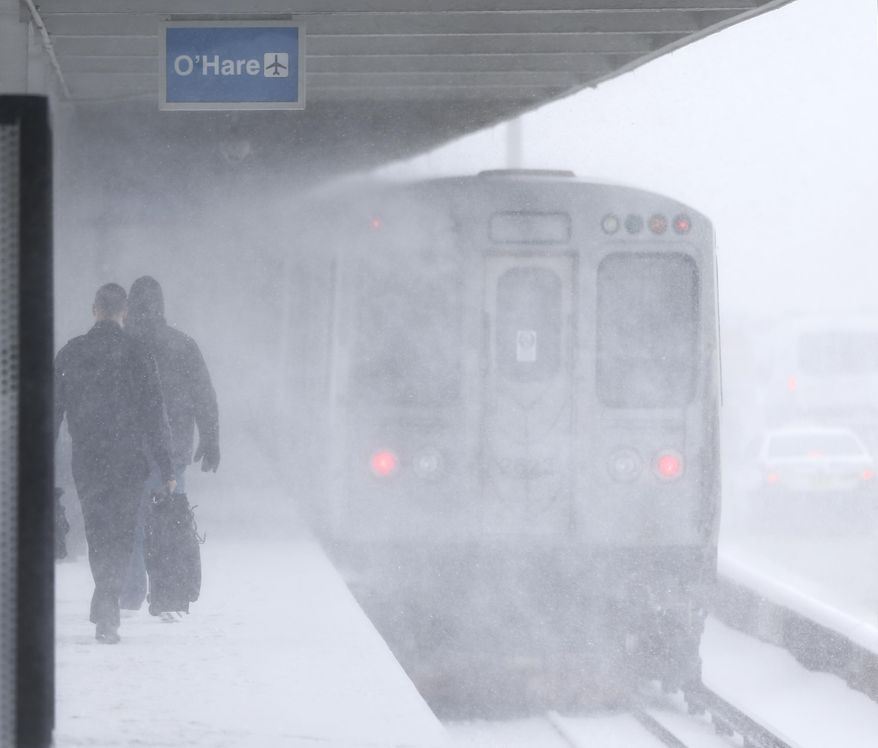 Travelers using the Chicago Transit Authority's Blue Line are hit by high winds and snow as a train heading to O'Hare International Airport passes at the Montrose Station, that runs parallel to the Kennedy Expressway, right, Tuesday, March 14, 2017, in Chicago. Much of the Midwest and beyond is getting snow as part of a two-day storm that forecasters say will yield between 3 to 6 inches of snow. (AP Photo/Charles Rex Arbogast)