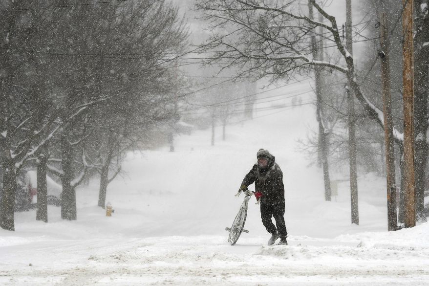 Jake Robinson walks his bike during a winter storm in Auburn, N.Y., Tuesday, March 14, 2017. A blustery, late-season storm clobbered the Northeast with sleet and heavy snow Tuesday, crippling much of the Washington-to-Boston corridor after a stretch of unusually mild winter weather that had people thinking spring was already here. (Kevin Rivoli/The Citizen via AP)