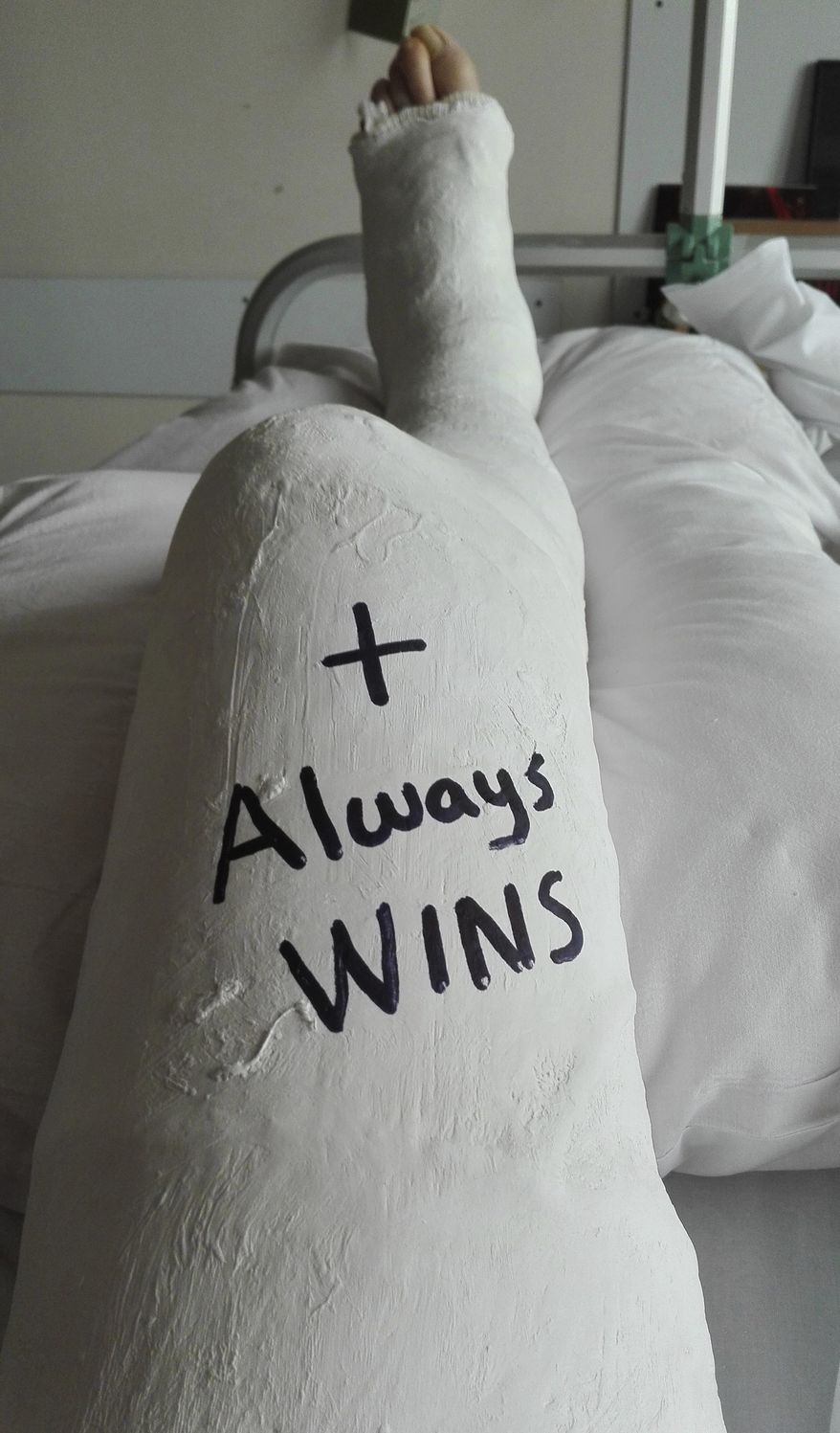 In this photo by Sebastian Bellin, taken in May 2016 while he was laying in a hospital bed in Brussels, the slogan 'positive always wins' is written on his cast. The former basketball player badly hurt in the suicide bomb attack on Brussels airport a year ago is urging the Belgian government to live up to its pledge to help the victims. (Sebastian Bellin via AP)