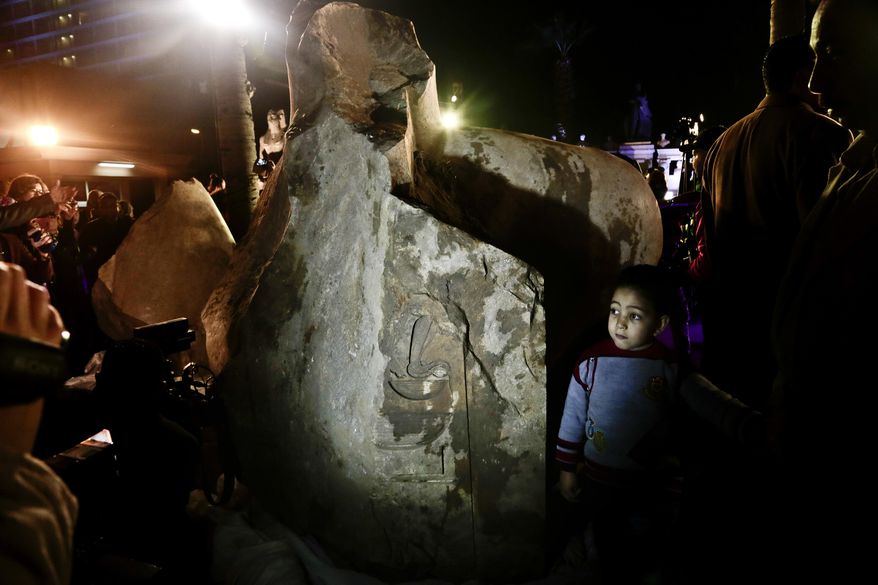 A boy looks at a stone, part of a statue of King Psamtek 1, after a press conference at the Egyptian museum in Cairo, Thursday, March 16, 2017. The three-ton torso of the massive statue was lifted on Monday from mud and groundwater where it was recently discovered in a Cairo slum. (AP Photo/Nariman El-Mofty)