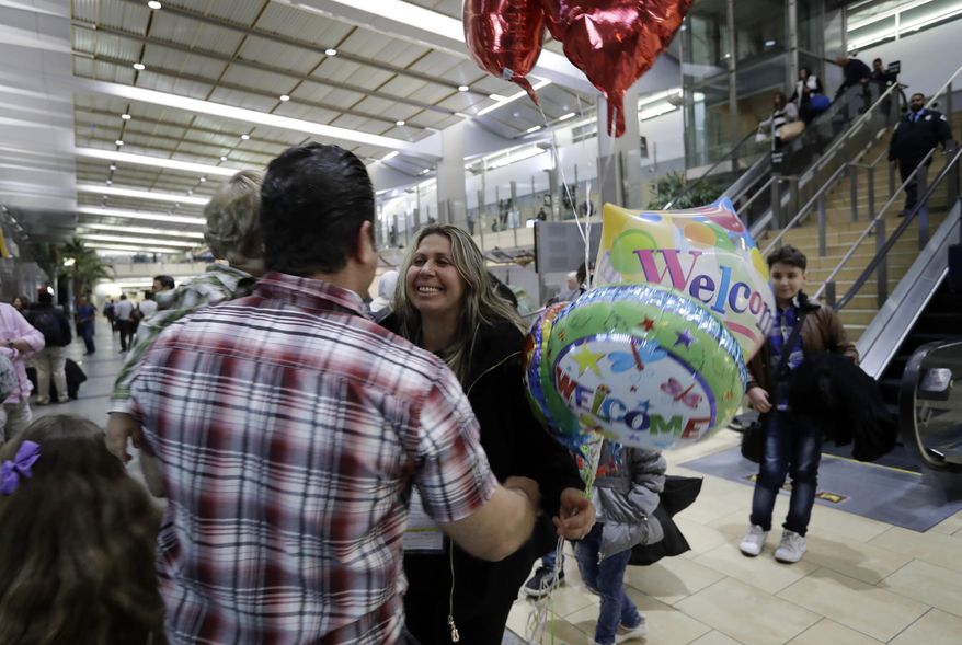 Nadia Hanan Madalo, center, hugs her brother Gassan Kakooz at the airport after arriving from Iraq Wednesday, March 15, 2017, in San Diego. Madalo and her family, refugees forced to flee their town of Batnaya, Iraq, after the Islamic State invaded and destroyed it several years ago, arrived in San Diego to be reunited with Madalo's siblings and mother. As they flew to the U.S. on Wednesday, a federal judge in Hawaii put a hold on President Trump's newest ban - the latest development in a fight between the administration and the courts that has injected more uncertainty into the lives of refugees. (AP Photo/Gregory Bull)