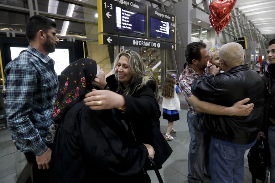 Nadia Hanan Madalo, center right, hugs her mother, Alyshooa Kannah, center left, at the airport after arriving from Iraq Wednesday, March 15, 2017, in San Diego. Madalo and her family, refugees forced to flee their town of Batnaya, Iraq, after the Islamic State invaded and destroyed it several years ago, arrived in San Diego to be reunited with Madalo's siblings and mother. As they flew to the U.S. on Wednesday, a federal judge in Hawaii put a hold on President Trump's newest ban - the latest development in a fight between the administration and the courts that has injected more uncertainty into the lives of refugees. (AP Photo/Gregory Bull)