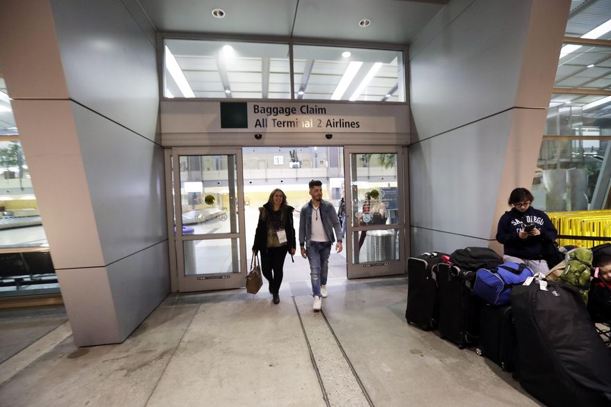 Nadia Hanan Madalo, left, walks with her son after arriving to the airport Thursday, March 16, 2017, in San Diego. Madalo and her family, refugees forced to flee their town of Batnaya, Iraq, after the Islamic State invaded and destroyed it several years ago, arrived in San Diego to be reunited with Madalo's siblings and mother. As they flew to the U.S. on Wednesday, a federal judge in Hawaii put a hold on President Trump's newest ban - the latest development in a fight between the administration and the courts that has injected more uncertainty into the lives of refugees. (AP Photo/Gregory Bull)
