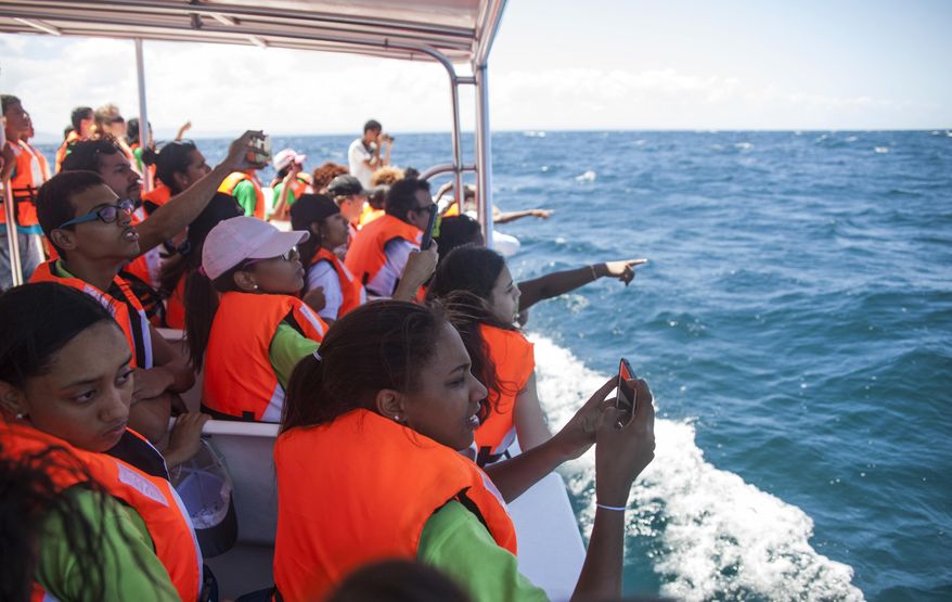 In this Tuesday, March 14, 2017 photo, students from the St. Rose Institute for Deaf Assistance spot whales during a tour off Samana, Dominican Republic. Dozens of them wore high-tech backpacks that turn whale songs into vibrations. Introducing deaf and hearing-impaired students to the whales and their music was the vision of Dominican artist and musician Maria Batlle, who founded the Muse Seek Project. (AP Photo/Tatiana Fernandez)