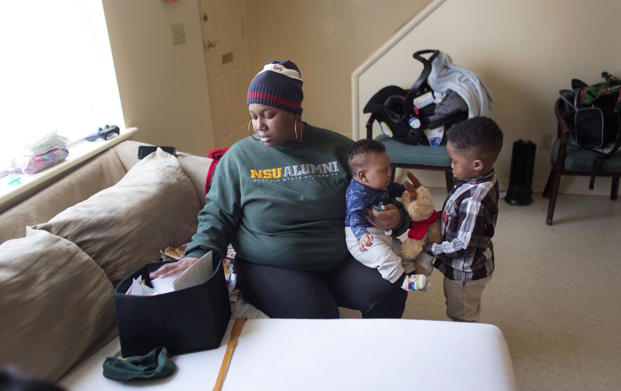 ADVANCE FOR SUNDAY, MARCH 19, 2017 - In this Feb. 13, 2017 photo, Tamaia Camp looks through her paper work as she sits with two of her children inside her home in Norfolk, Va. Camp is being charged nearly $19,000 in tolls and late fees from Elizabeth River Crossings. (L. Todd Spencer/The Virginian-Pilot via AP)