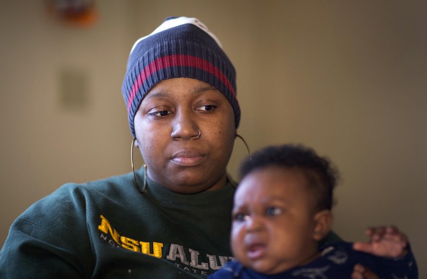 ADVANCE FOR SUNDAY, MARCH 19, 2017 - In this Feb. 13, 2017 photo, Tamaia Camp pauses while looking through her paper work as she sits with three month old Devon Smith, inside her home in Norfolk, Va. Camp is being charged nearly $19,000 in tolls and late fees from Elizabeth River Crossings. (L. Todd Spencer/The Virginian-Pilot via AP)