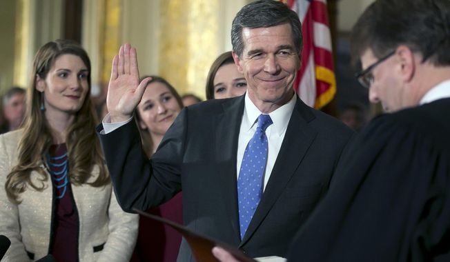 FILE - In this Friday, Jan. 6, 2017, file photo, Roy Cooper is ceremonially sworn in as Governor of North Carolina by Chief Justice Mark Martin during a ceremony at the Executive Mansion in Raleigh, N.C. North Carolina judges issued partial victories Friday to both Republican legislators and new Democratic Gov. Roy Cooper over laws designed to undercut his powers. The judicial panel threw out laws approved two weeks before Cooper took office limiting his authority in carrying out elections and giving civil service job protections to hundreds of former Republican Gov. Pat McCrory’s political appointees.(Robert Willett/The News &amp;amp; Observer via AP, File)