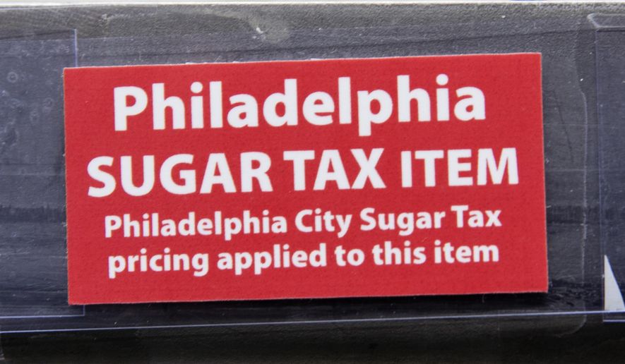 This March 16, 2017, photo shows a sticker alerting customers of the sugar tax posted by sweetened beverages at the IGA supermarket in the Port Richmond neighborhood of Philadelphia. (Associated Press) **FILE**