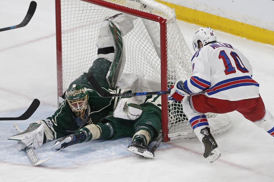 New York Rangers&#39; J.T. Miller, right, looks for a rebound while Minnesota Wild goalie Devan Dubnyk, with the assistance of Jared Spurgeon, smothers a shot during the first period of an NHL hockey game Saturday, March 18, 2017, in St. Paul, Minn. (AP Photo/Jim Mone)