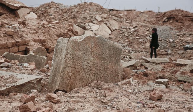 FILE - In this Wednesday, Dec. 14, 2016 file photo, a stone tablet with cuneiform writing in the foreground as UNESCO&#x27;s Iraq representative Louise Haxthausen documents the damage wreaked by the Islamic State group at the ancient site of Nimrud, Iraq. France is trying to raise tens of millions of dollars from international donors who gathered Monday March 20, 2017, to protect cultural heritage sites threatened by war and the kind of destruction carried out by Islamic State militants. (AP Photo/Maya Alleruzzo, File)