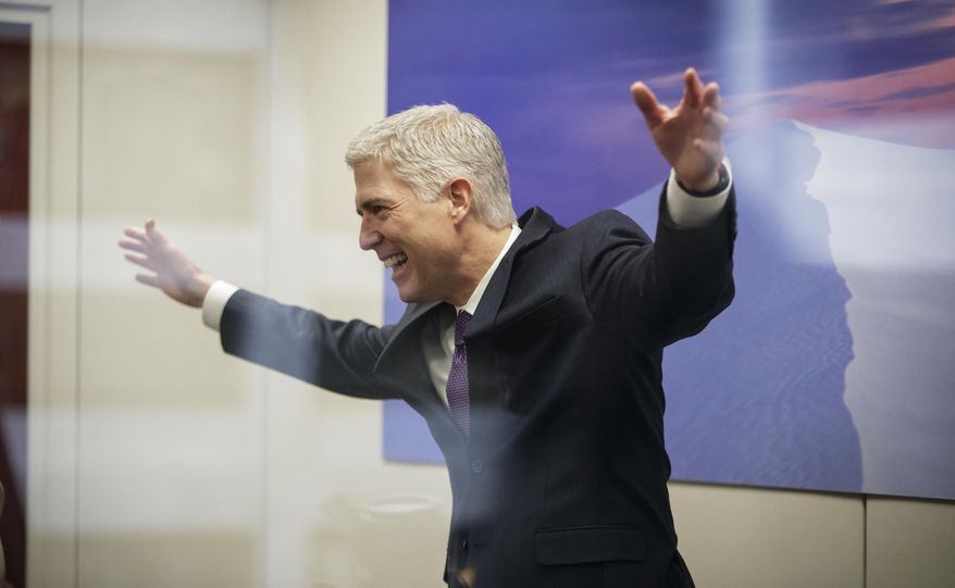 FILE - In this Feb. 27, 2017, file photo, Supreme Court Justice nominee Neil Gorsuch, seen through glass, makes an animated gesture while speaking with staff members before his meeting with Sen. Tom Udall, D-N.M., on Capitol Hill in Washington.Gorsuch is roundly described by colleagues and friends as a silver-haired combination of wicked smarts, down-to-earth modesty, disarming warmth and careful deliberation. His critics largely agree with that view of the self-described “workaday judge” in polyester robes. Even so, they’re not sure it’s enough to warrant giving him a spot on the court.  (AP Photo/J. Scott Applewhite, File)