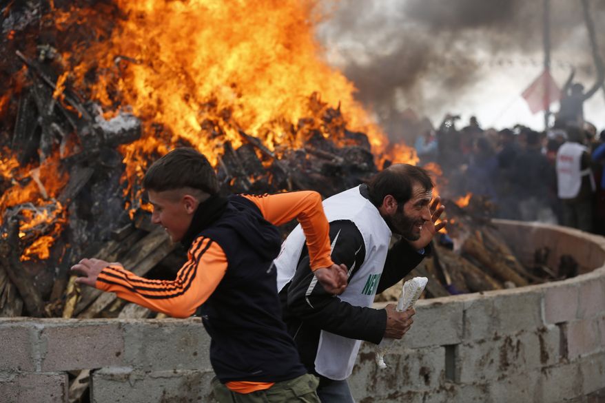 Men run in front of a bonfire during the Newroz celebration, in Diyarbakir, southeastern Turkey, Tuesday, March 21, 2017. Thousands celebrated the Newroz festival in Istanbul and in Diyarbakir, a mainly Kurdish city in a region where Kurdish militants regularly clash with government forces. In Turkey, the spring festival traditionally serves as an occasion to demand more rights for the Kurdish minority.(AP Photo/Lefteris Pitarakis)