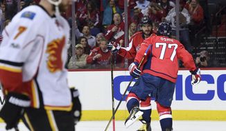 Washington Capitals right wing T.J. Oshie (77) celebrates his goal with left wing Alex Ovechkin (8) as Calgary Flames defenseman T.J. Brodie (7) skates by during the second period of an NHL hockey game, Tuesday, March 21, 2017, in Washington. (AP Photo/Molly Riley)
