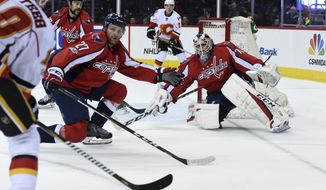 Washington Capitals defenseman Karl Alzner (27) defends the net with goalie Braden Holtby (70) against Calgary Flames right wing Kris Versteeg (10), far left, during the first period of an NHL hockey game, Tuesday, March 21, 2017, in Washington. (AP Photo/Molly Riley)