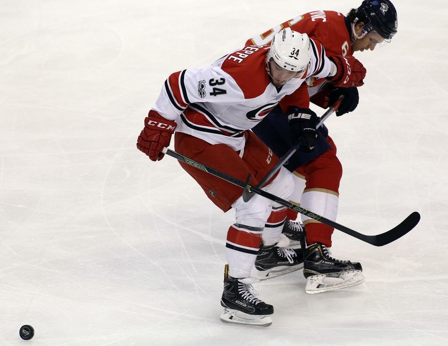 Carolina Hurricanes&#39; Phillip Di Giuseppe (34) and Florida Panthers&#39; Alex Petrovic, right, look for the puck during the first period of an NHL hockey game, Tuesday, March 21, 2017, in Sunrise, Fla. (AP Photo/Luis M. Alvarez)