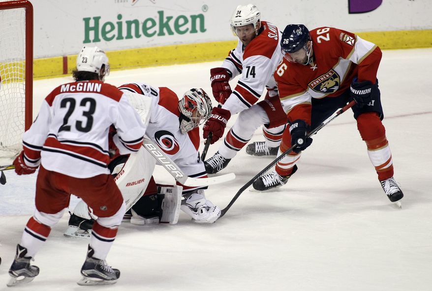 Carolina Hurricanes goalie Cam Ward, center, holds the puck on Florida Panthers&#39; Thomas Vanek, of Austria (26) as teammates Brock McGinn (23) and Jaccob Slavin (74) defend during the first period of an NHL hockey game, Tuesday, March 21, 2017, in Sunrise, Fla. (AP Photo/Luis M. Alvarez)