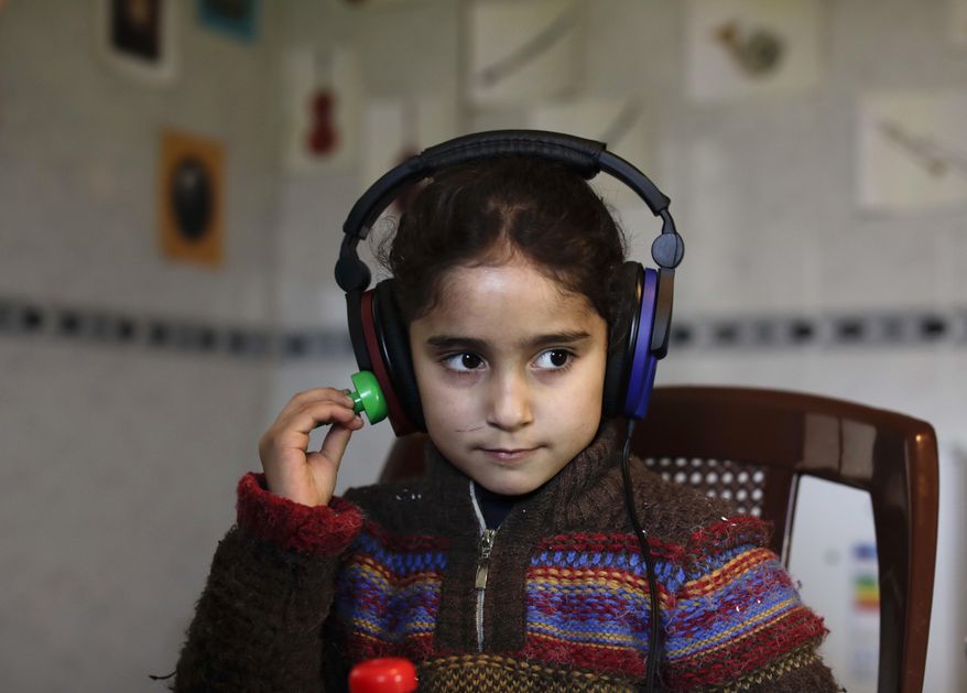 In this Sunday, March 12, 2017 photo, Syrian refugees Aya al-Souqi, receives her first hearing test by Zaineb Abdulla, the Vice President of "Deaf Planet Soul" Chicago hearing charity at Joub Jannine village in the Bekaa valley, east Lebanon, Sunday, Sunday, March 12, 2017. (AP Photo/Hassan Ammar)