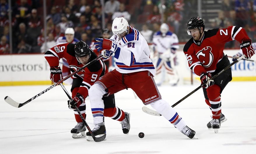 New York Rangers right wing Rick Nash, center, attacks as New Jersey Devils left wing Taylor Hall, left, and defenseman Damon Severson challenge him during the first period of an NHL hockey game, Tuesday, March 21, 2017, in Newark, N.J. (AP Photo/Julio Cortez)