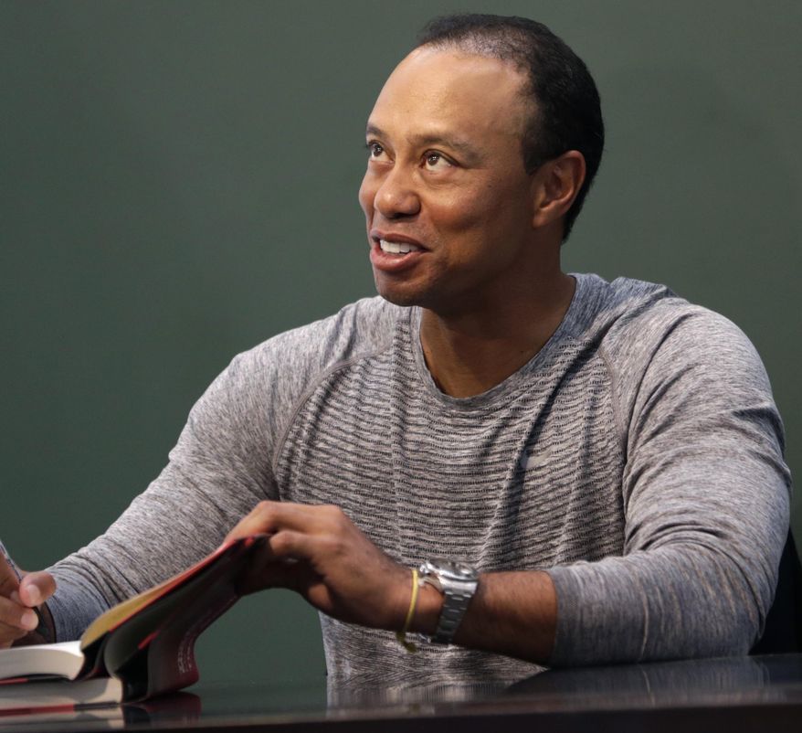 Golfer Tiger Woods signs copies of his new book in New York, Monday, March 20, 2017. (AP Photo/Seth Wenig)
