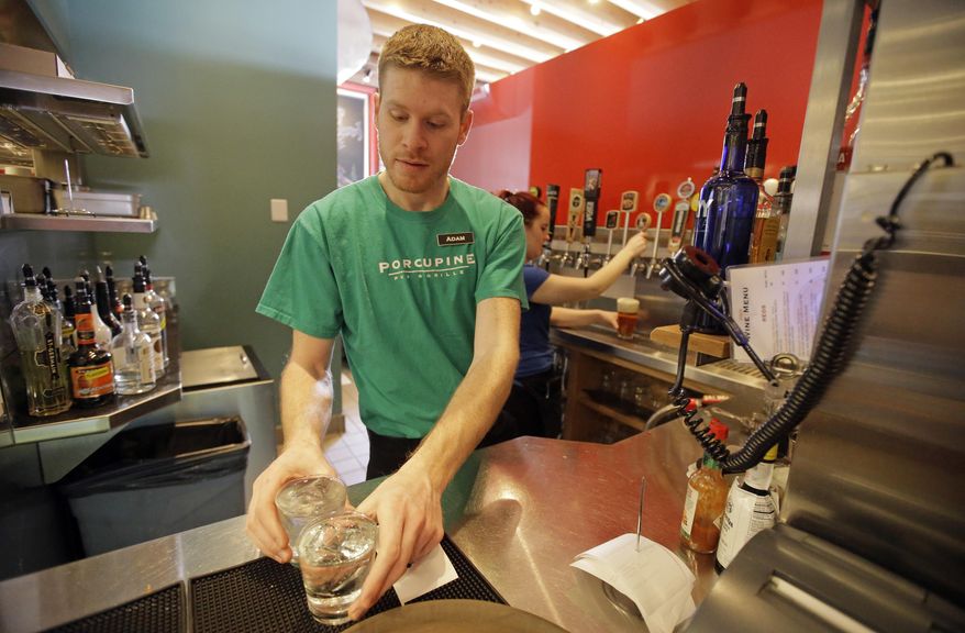 FILE - This March 1, 2017, file photo, Porcupine Pub & Grille server Adam Francis pours drinks behind the "Zion Curtain," in Salt Lake City. Utah restaurants will have more freedom to mix and pour alcohol in front of customers under a measure awaiting Gov. Gary Herbert's signature. But other concessions in the proposal aimed at keeping kids away from bars could complicate restaurant seating and leave some establishments keeping up their frosted glass walls known as "Zion Curtains," used to hide the preparation of drinks. (AP Photo/Rick Bowmer, File )