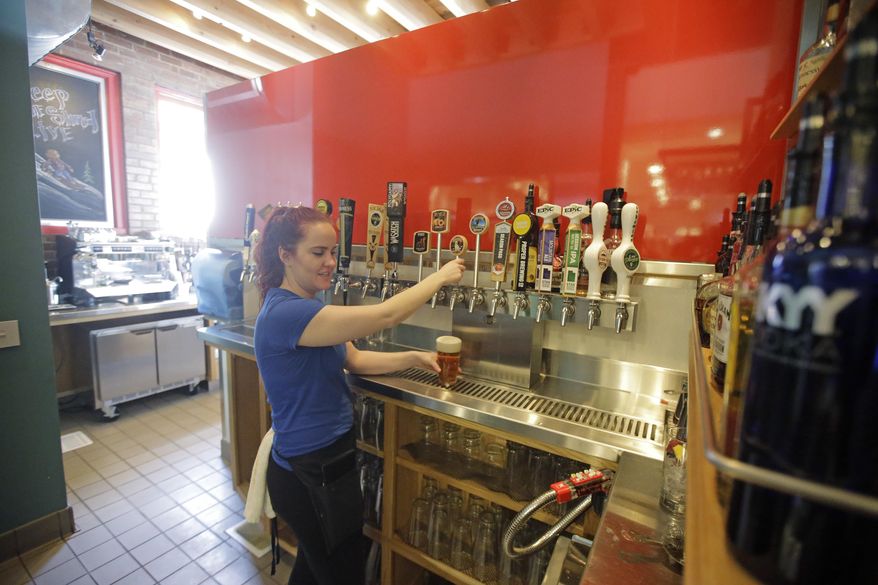 FILE - This March 1, 2017, file photo, Porcupine Pub & Grille server Sarah Fisher pours a beer behind the "Zion Curtain," in Salt Lake City. Utah restaurants will have more freedom to mix and pour alcohol in front of customers under a measure awaiting Gov. Gary Herbert's signature. But other concessions in the proposal aimed at keeping kids away from bars could complicate restaurant seating and leave some establishments keeping up their frosted glass walls known as "Zion Curtains," used to hide the preparation of drinks. (AP Photo/Rick Bowmer, File)