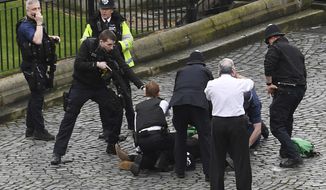 A policeman points a gun at a man on the floor as emergency services attend the scene outside the Palace of Westminster, London, Wednesday, March 22, 2017.  London police say they are treating a gun and knife incident at Britain&#x27;s Parliament &quot;as a terrorist incident until we know otherwise.&quot; The Metropolitan Police says in a statement that the incident is ongoing. It is urging people to stay away from the area. Officials say a man with a knife attacked a police officer at Parliament and was shot by officers. Nearby, witnesses say a vehicle struck several people on the Westminster Bridge.  (Stefan Rousseau/PA via AP).