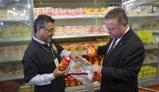 Brazil&#x27;s Agriculture Minister Blairo Maggi, right, accompanied by a sanitary inspection agent, collect meat products for testing, in a supermarket in Brasilia, Brazil, Wednesday, March 22, 2017. South Africa is partially suspending imports of Brazilian meat, the latest country to do so in the wake of an inspection scandal. Brazilian investigators charge that health inspectors in the South American country were bribed to overlook the sale of expired meats and chemicals and other products were added to meat to improve its appearance and smell. (AP Photo/Eraldo Peres)