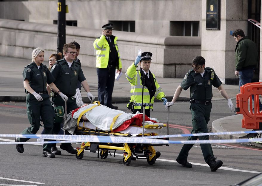 Emergency services staff provide medical attention close to the Houses of Parliament in London, Wednesday, March 22, 2017. London police say they are treating a gun and knife incident at Britain's Parliament "as a terrorist incident until we know otherwise." The Metropolitan Police says in a statement that the incident is ongoing. Officials say a man with a knife attacked a police officer at Parliament and was shot by officers. Nearby, witnesses say a vehicle struck several people on the Westminster Bridge. (AP Photo/Matt Dunham)