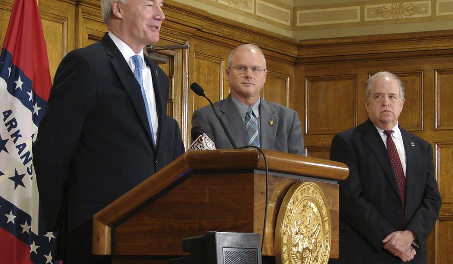 Gov. Asa Hutchinson, left, speaks to reporters Wednesday, March 22, 2017, at the state Capitol in Little Rock, Arkansas, after signing a bill allowing concealed handguns at colleges, bars and most government buildings if a permit-holder has completed eight hours of active-shooter training. (AP Photo/Kelly P. Kissel)