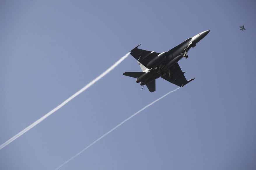 In this Monday, March 20, 2017, file photograph, an F-18 fighter jet flies over the USS George H.W. Bush as the vessel travels toward the Strait of Hormuz. The arrival of the nuclear-powered aircraft carrier to the Persian Gulf marks the first such deployment under new U.S. President Donald Trump. (AP Photo/Jon Gambrell) ** FILE **