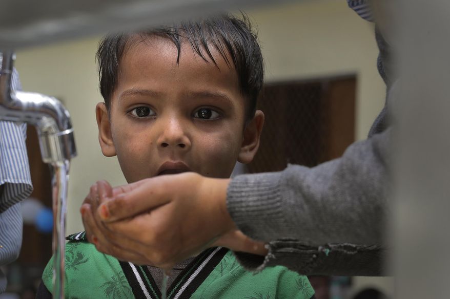 A boy helps another to drink water from his hand from a newly set up water filtration tower at a school in Nai Basti Village, some 55 kilometers (35 miles) from in New Delhi, India, Wednesday, March 22, 2017. Schoolchildren cheered and village women clapped as a gush of clean water flowed through a set of gleaming steel taps connected to a newly installed water filtration plant in a dusty north Indian village on Wednesday. (AP Photo/Manish Swarup)
